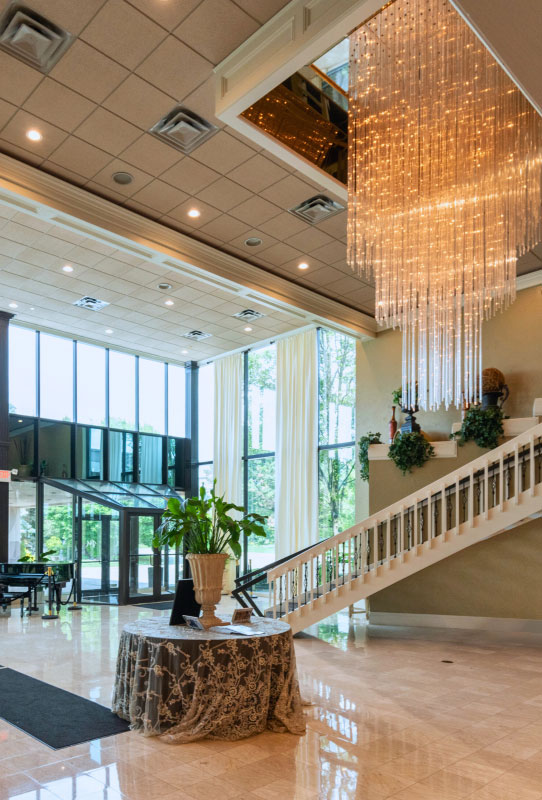 Lobby of The Mirage Banquet & Event Center in Clinton Township, MI featuring a grand glass chandelier, spiral staircase, and vibrant cinematic design