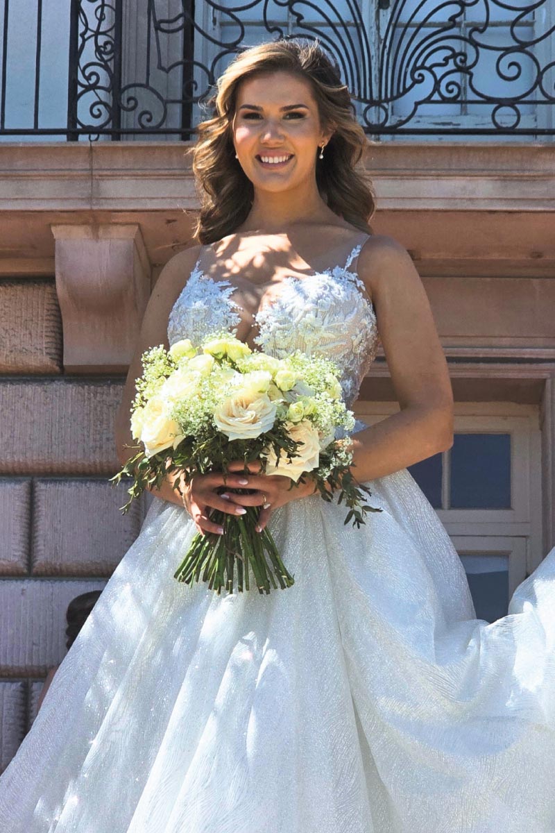 Wedding portrait of Erica holding a stunning floral bouquet designed by Juha Qureshi at her Michigan wedding, styled by a premier wedding decorator in Michigan.