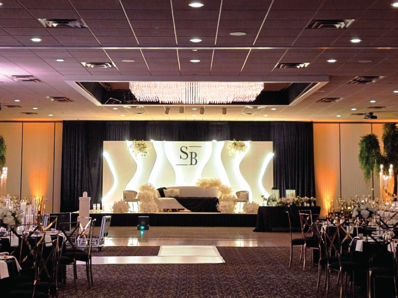 Modern, unique wedding stage décor in Michigan with waved structures and edge lighting, created by a leading wedding decorator in Michigan.