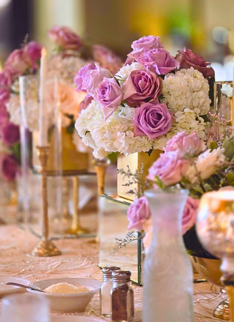 Low blush & lavender centerpieces: Lavender roses and ivory hydrangeas in mirrored gold vessels, running the length of a reception table — a softer, more intimate expression of fresh flowers for weddings in Metro Detroit.