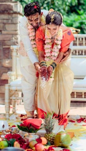 A couple exchanging vows under a stunning mandap decorator in Metro Detroit by Bridal Insignia — adorned with fresh florals and elegant draping